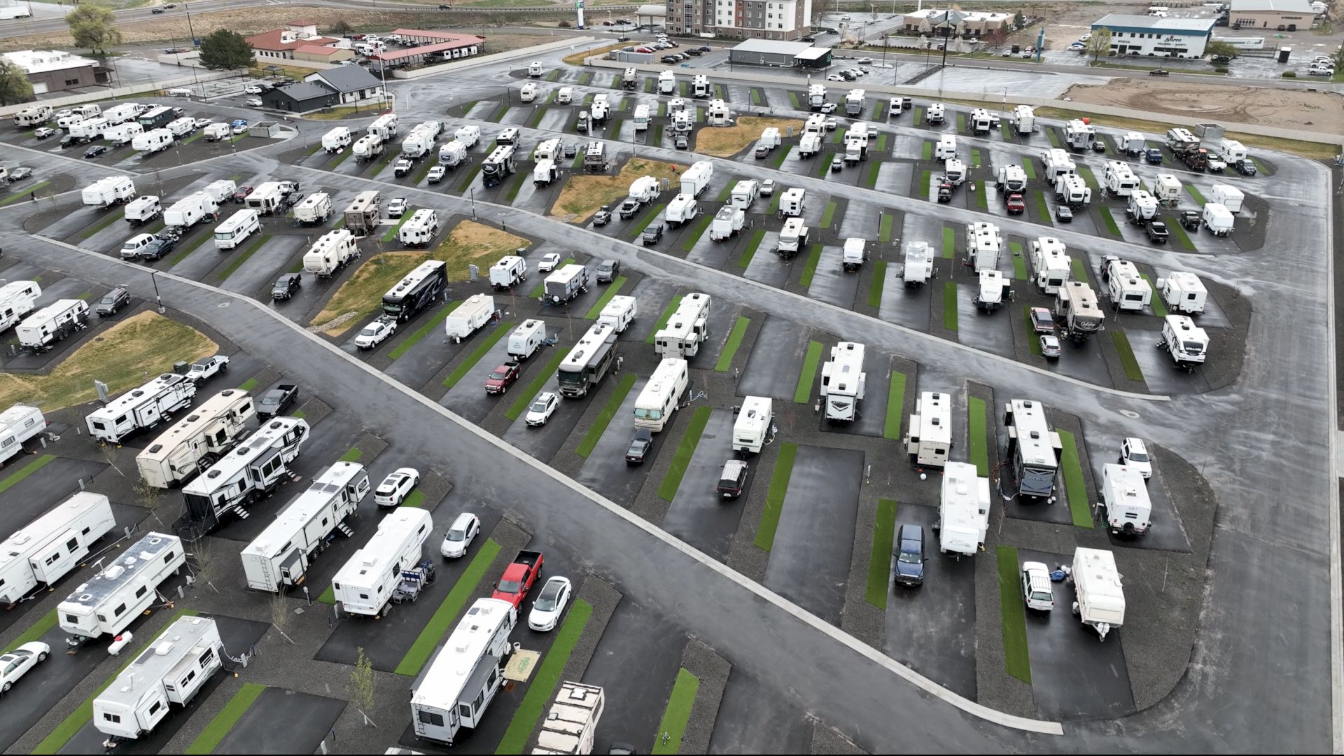 Aerial view of a large RV and camper lot, with rows of mobile homes and trailers parked on neat lots and winding streets&mdash;busier than typical.
