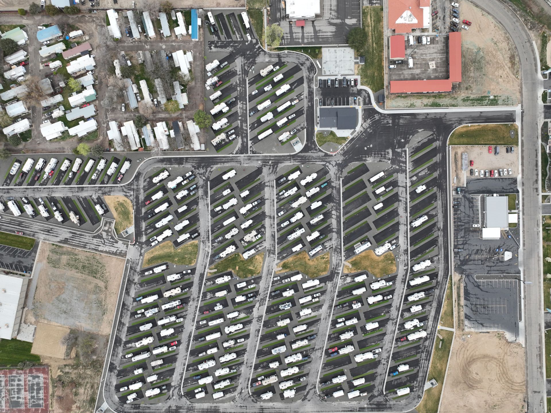 An aerial view of a trailer/RV park with many parked vehicles, buildings, and internal roads around the numbered lots.