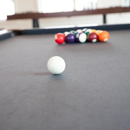 A small white ball on a path with colorful items and a blurred figure or objects in the distance, set on a smooth surface.